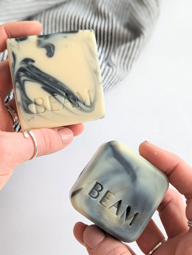 BEAM natural body care awaken natural soap. A large and small size black and white soap held in hands 